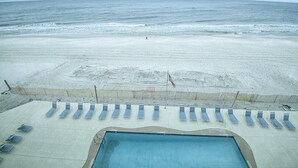 Blick auf einen Strand mit Pool und Liegestühlen.
