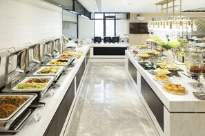 Montaje de bufé con diferentes alimentos y una cocina moderna al fondo.