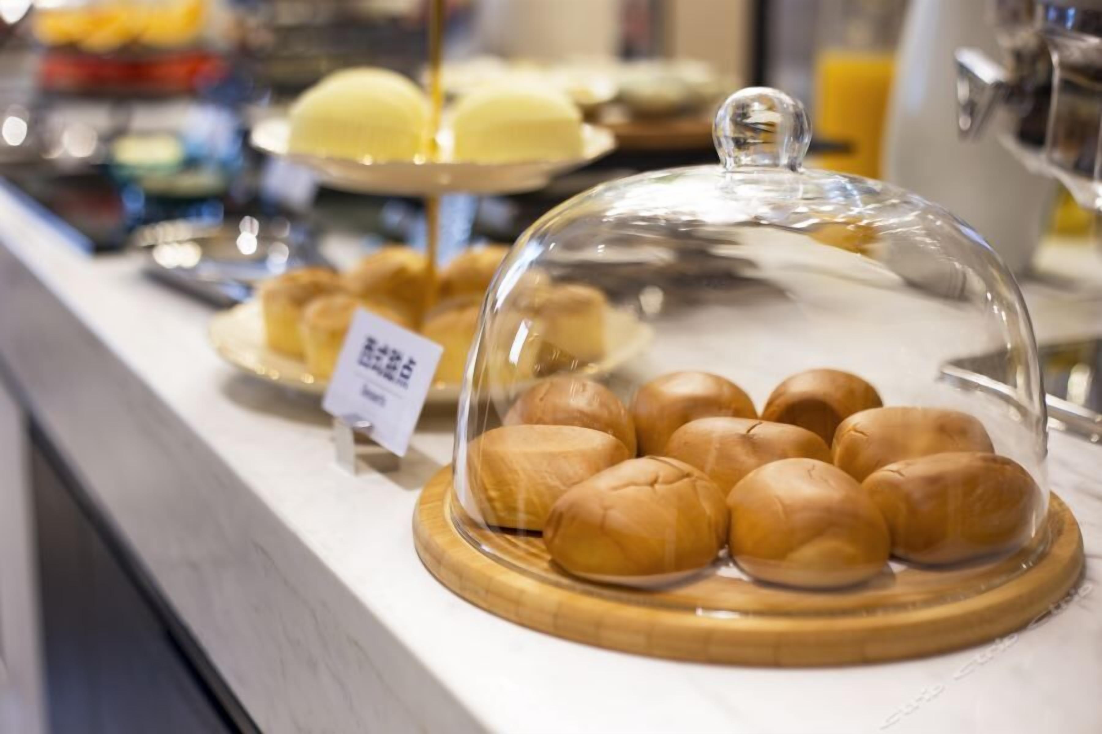 Una vitrina de panadería con panes y pasteles bajo una cúpula de vidrio.