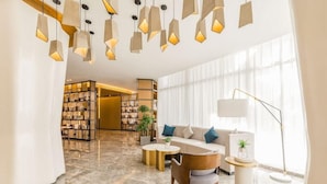 A modern hotel lobby with a sofa, coffee table, and bookshelves.