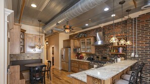 A spacious kitchen with wooden cabinets, a large island, and a brick wall.