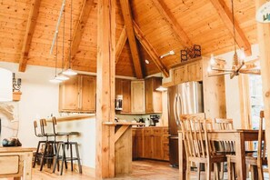 Une cuisine rustique avec des poutres en bois, un îlot central, des tabourets de bar et une table à manger.