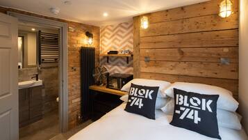 A bedroom with a wooden headboard, two pillows with 'blok 74' text, a bedside table, a radiator, and a mirror.