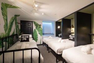 Una habitación de hotel con cama, un escritorio pequeño, una silla, un espejo y un ventanal grande.