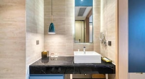 A modern bathroom with a marble countertop, a white sink, a mirror, and a pendant light.