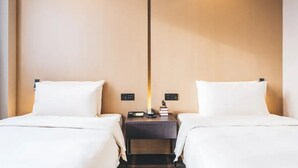 A hotel room with two beds, a nightstand with a lamp, and a wall-mounted control panel. - Atour Light (Hangzhou)