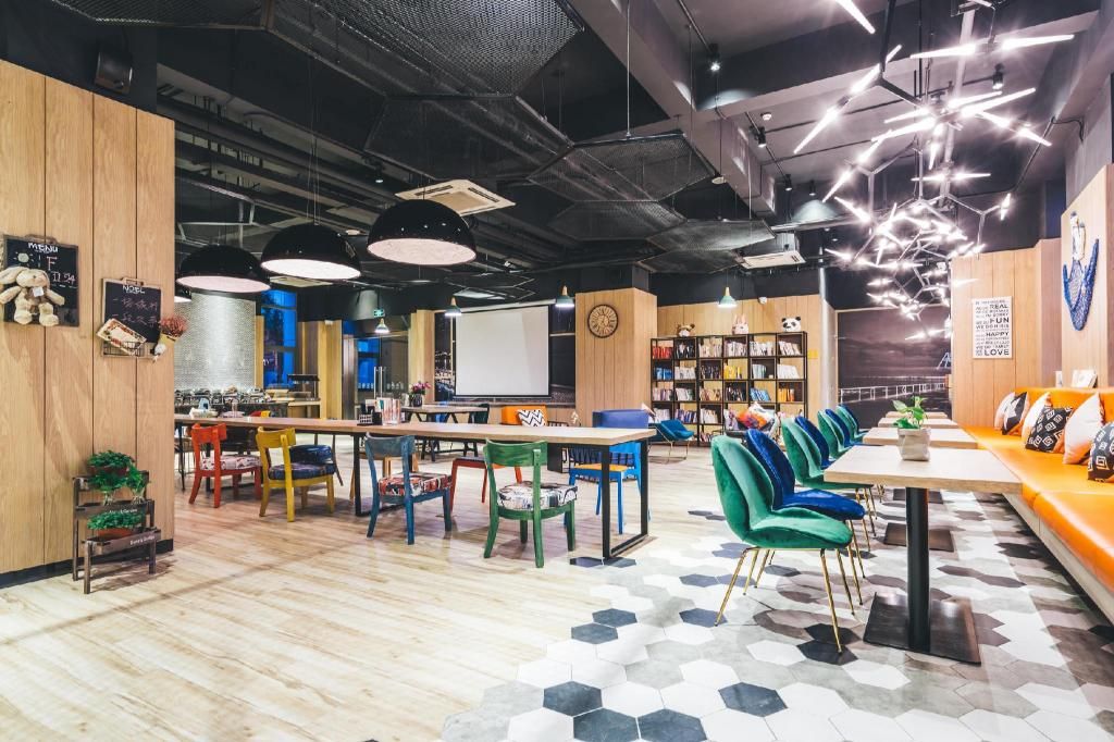 A modern library with wooden walls, hexagonal patterned flooring, and a variety of seating options including tables and chairs.