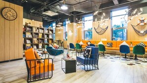 A modern library with bookshelves, comfortable seating, and large windows. - Atour Light (Hangzhou)