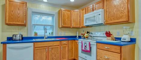 A kitchen with wooden cabinets, a white stove, a microwave, a toaster, and a blue countertop.