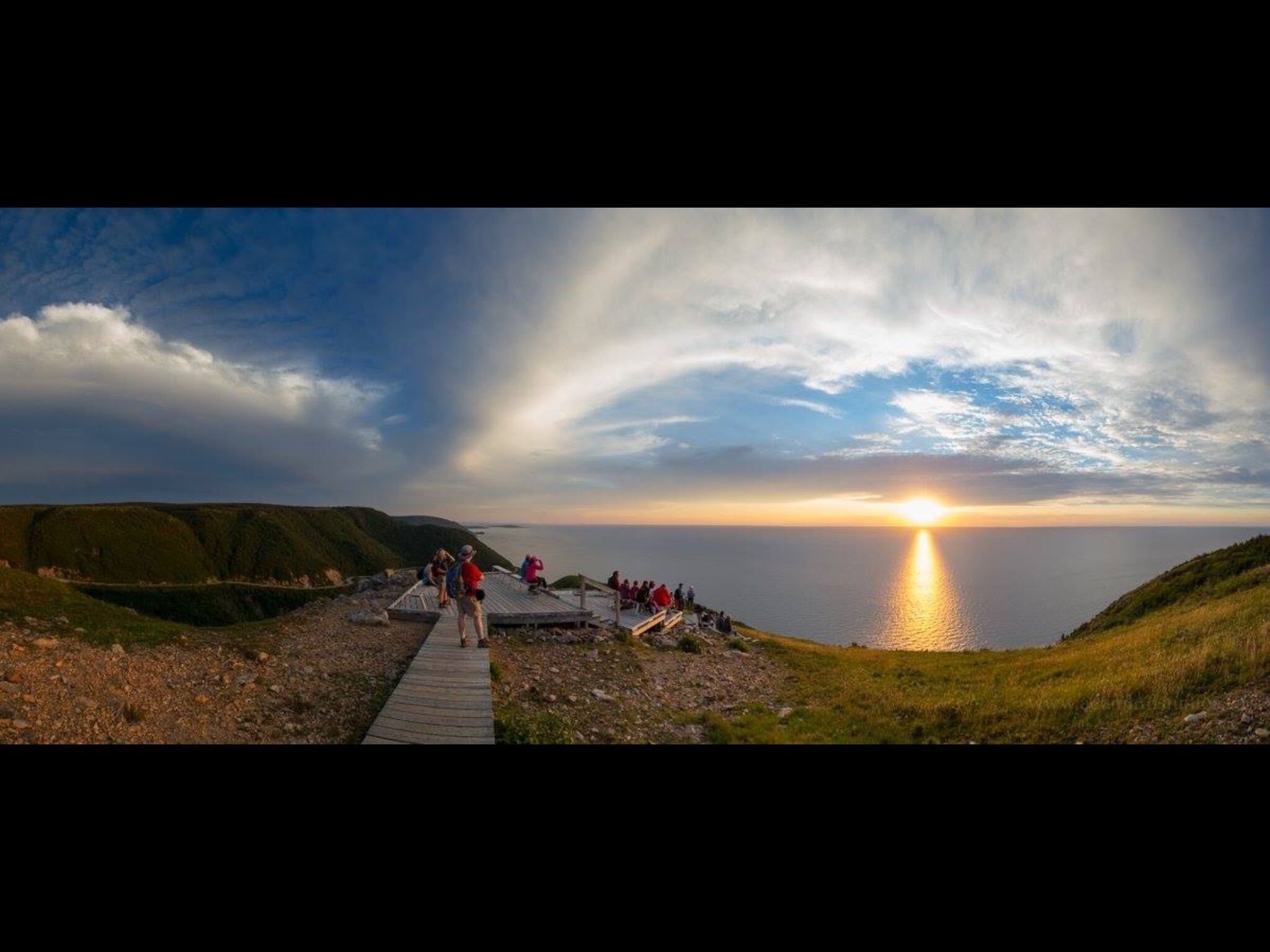 Ein Sonnenuntergangsblick von einer Uferpromenade, während Menschen die Landschaft genießen.