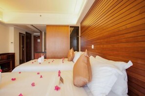 A hotel room with two beds, wooden paneling on the walls, and a visible door leading to another room. - Zhujiang Crystal Hotel (Wuzhishan)