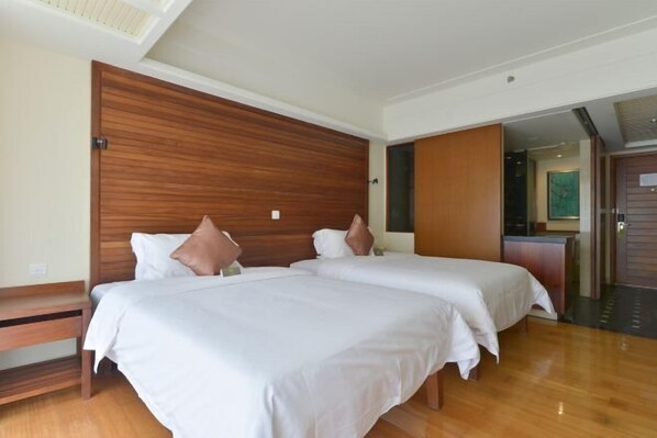 A hotel room with two beds, wooden headboard, and a wooden floor. - Zhujiang Crystal Hotel (Wuzhishan)
