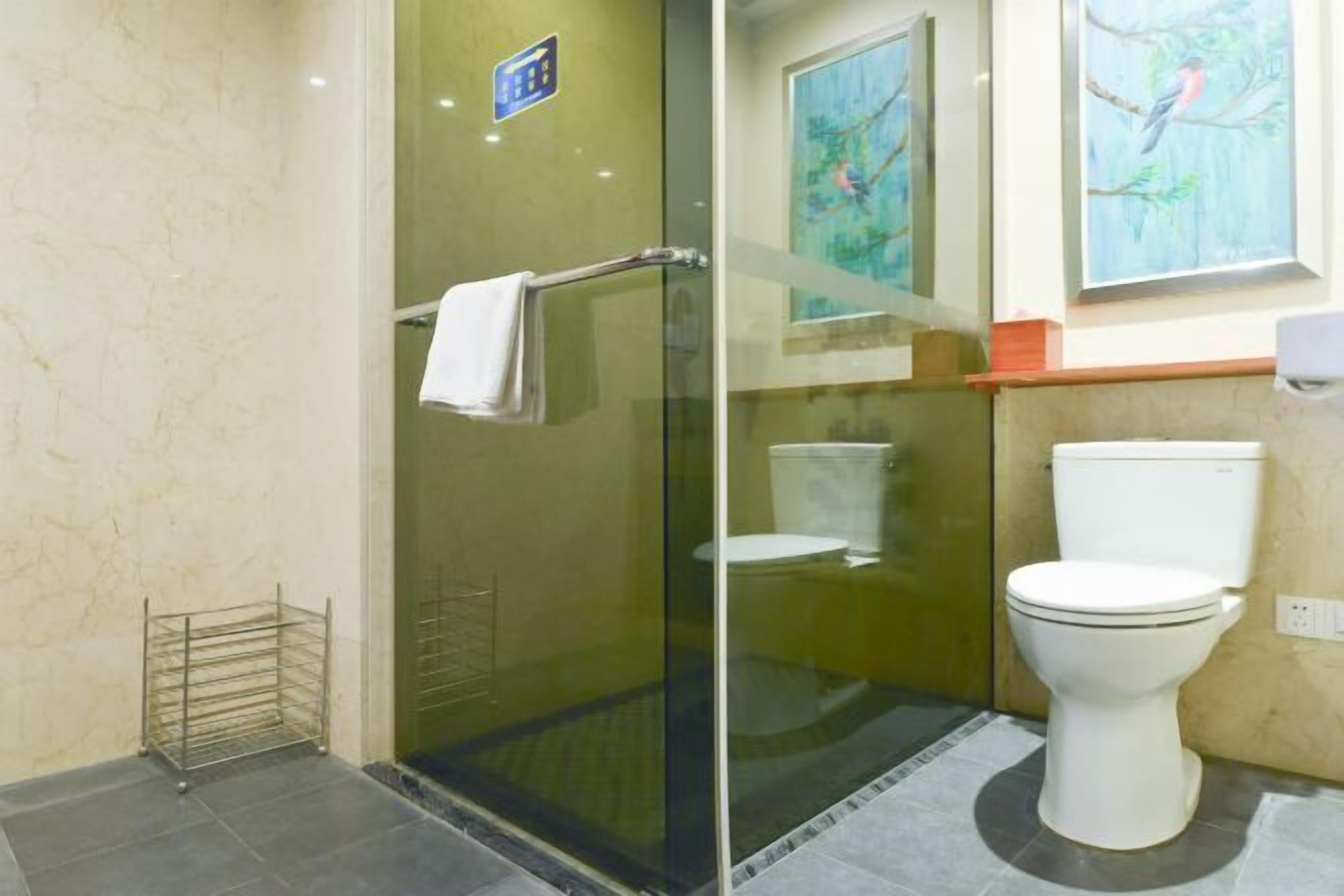 A bathroom with a glass-enclosed shower, a toilet, and a towel rack.