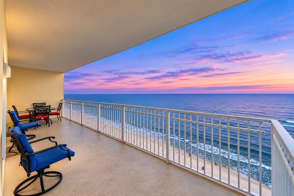 A balcony with a view of the ocean, equipped with a table and chairs.