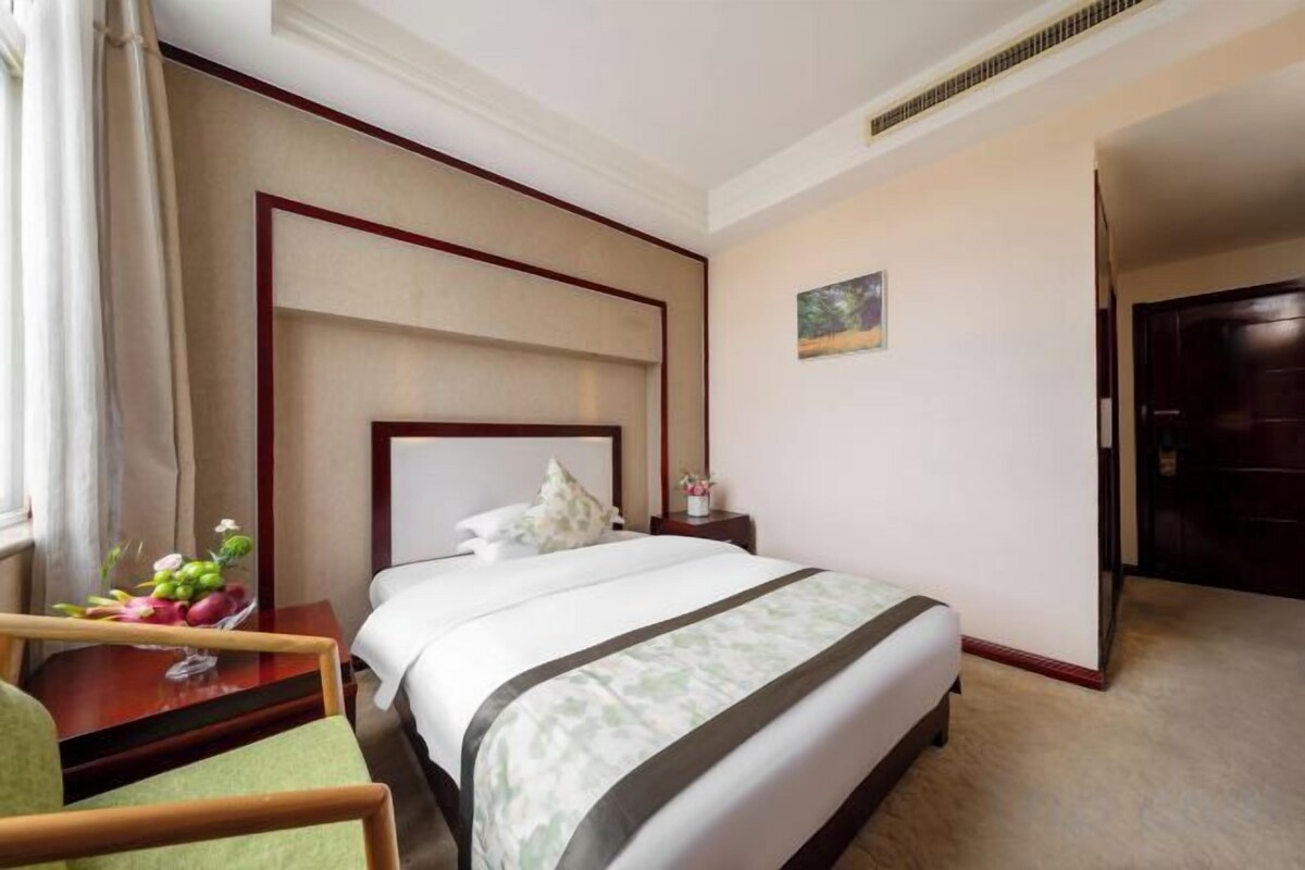 A hotel room with a bed, a desk, and a chair.