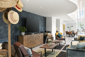 A modern living room with a flat-screen TV, wooden cabinets, and a dining area with chairs and a table. - Citadines Confluent Nantes (Nantes)