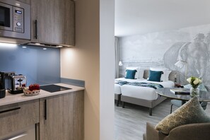 Een moderne keuken met een ingebouwde magnetron en broodrooster, een eethoek met een glazen tafel, en een slaapkamer met een groot bed en een muurschildering van een olifant.