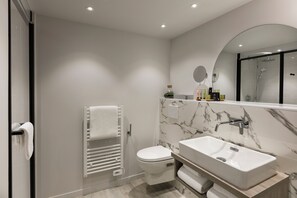 Een moderne badkamer met een wit toilet, een grote wastafel en een spiegel boven de wastafel.