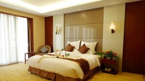 A hotel room with a large bed, a chair, a nightstand with a lamp, and a window with curtains. - Fuquan Grand Hotel (Pingdingshan)