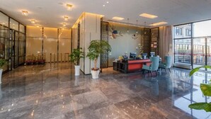 A modern lobby with a reception desk, seating area, and large windows offering a view of the city. - Bailing Hot Spring Hotel (Anshun)