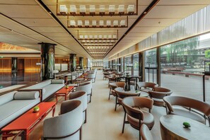 A modern interior with seating areas, tables, and large windows offering views of the outdoors. - Hualuxe Xi an Tanghua (Xi'an)
