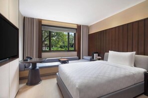 A modern hotel room with a large bed, a seating area with a table, and a TV. - Hualuxe Xi an Tanghua (Xi'an)