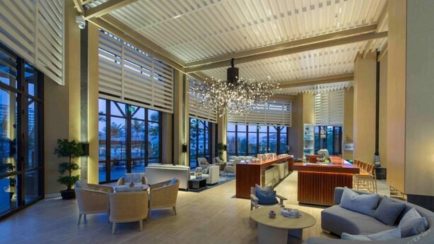 A spacious, modern hotel lobby with large windows, a central seating area, and a bar. - Hongtang Bay Jianguo Resort Sanya (Sanya)