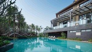 A modern hotel with a swimming pool, outdoor seating, and tropical vegetation. - Hongtang Bay Jianguo Resort Sanya (Sanya)