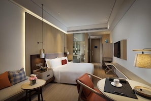 A modern hotel room with a bed, bedside table, chair, and a small table with a cup and saucer. - Hongtang Bay Jianguo Resort Sanya (Sanya)
