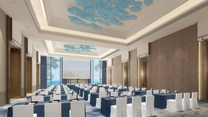 A conference room with rows of tables and chairs, a large screen at the front, and a patterned wall on one side. - Hongtang Bay Jianguo Resort Sanya (Sanya)