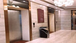 A modern elevator interior with a marble wall, a digital display, and a sign with text. - Golden Orange Smart Hotel (Shenzhen)
