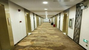 A long, carpeted hallway with doors on both sides, leading to individual rooms. - Golden Orange Smart Hotel (Shenzhen)