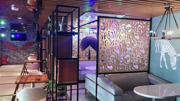 A modern interior with a seating area, tables, and decorative panels. - Golden Orange Smart Hotel (Shenzhen)
