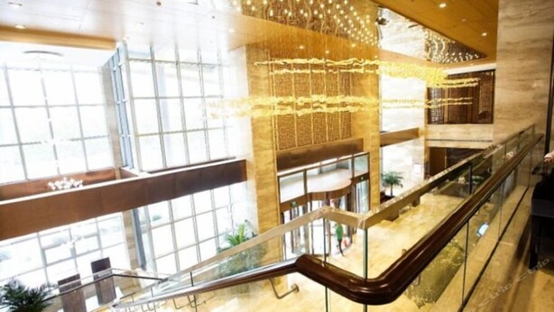 Un interior de varios niveles con barandas de vidrio, ventanas amplias e iluminación decorativa.