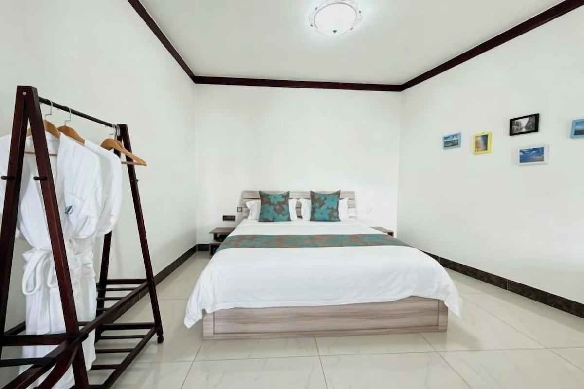 A bedroom with a bed, a wooden wardrobe, and a nightstand.