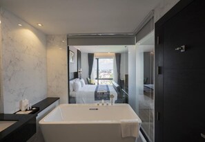Ein modernes Badezimmer mit einer großen Badewanne, einer Glasdusche und Blick auf die Stadt durch das Fenster.