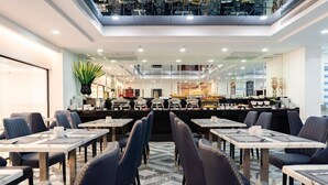 A modern dining area with tables and chairs, a central buffet, and a glass ceiling. - Surestay Hotel by Best Western Vientiane (Vientiane)