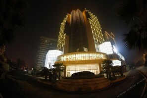 A modern hotel with a prominent central tower and a well-lit entrance. - International MGM Xiangtan (Xiangtan)