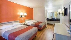A hotel room with two beds, a desk, a mirror, and a bathroom visible in the background. - Magnuson Hotel Baton Rouge East (Baton Rouge)