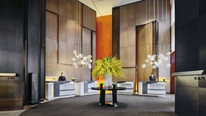 A modern reception area with a central round table, two reception desks, and a large decorative plant. - Intercontinental Xi an North (Xi'an)