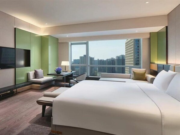 Ein modernes Hotelzimmer mit einem großen Bett, einer Sitzecke und Blick auf die Stadt.