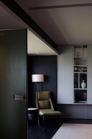 A modern room with a dark wall, a green chair, a white lamp, and a built-in shelf with decorative items. - Intercontinental Xi an North (Xi'an)