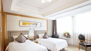 A hotel room with two beds, a small table with a chair, a painting on the wall, and a window with curtains. - Friend Hotel Shanghai (Shanghai)