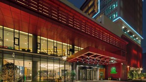 A modern hotel with a red facade, large glass windows, and a Holiday Inn sign. - Holiday Inn Chengdu Airport (Chengdu)