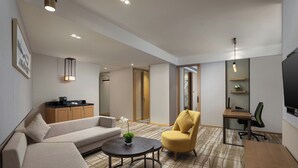 A modern living room with a sofa, armchair, round table, and a TV. - Holiday Inn Chengdu Airport (Chengdu)