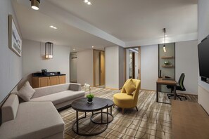 A modern living room with a sofa, armchair, round table, and a TV. - Holiday Inn Chengdu Airport (Chengdu)