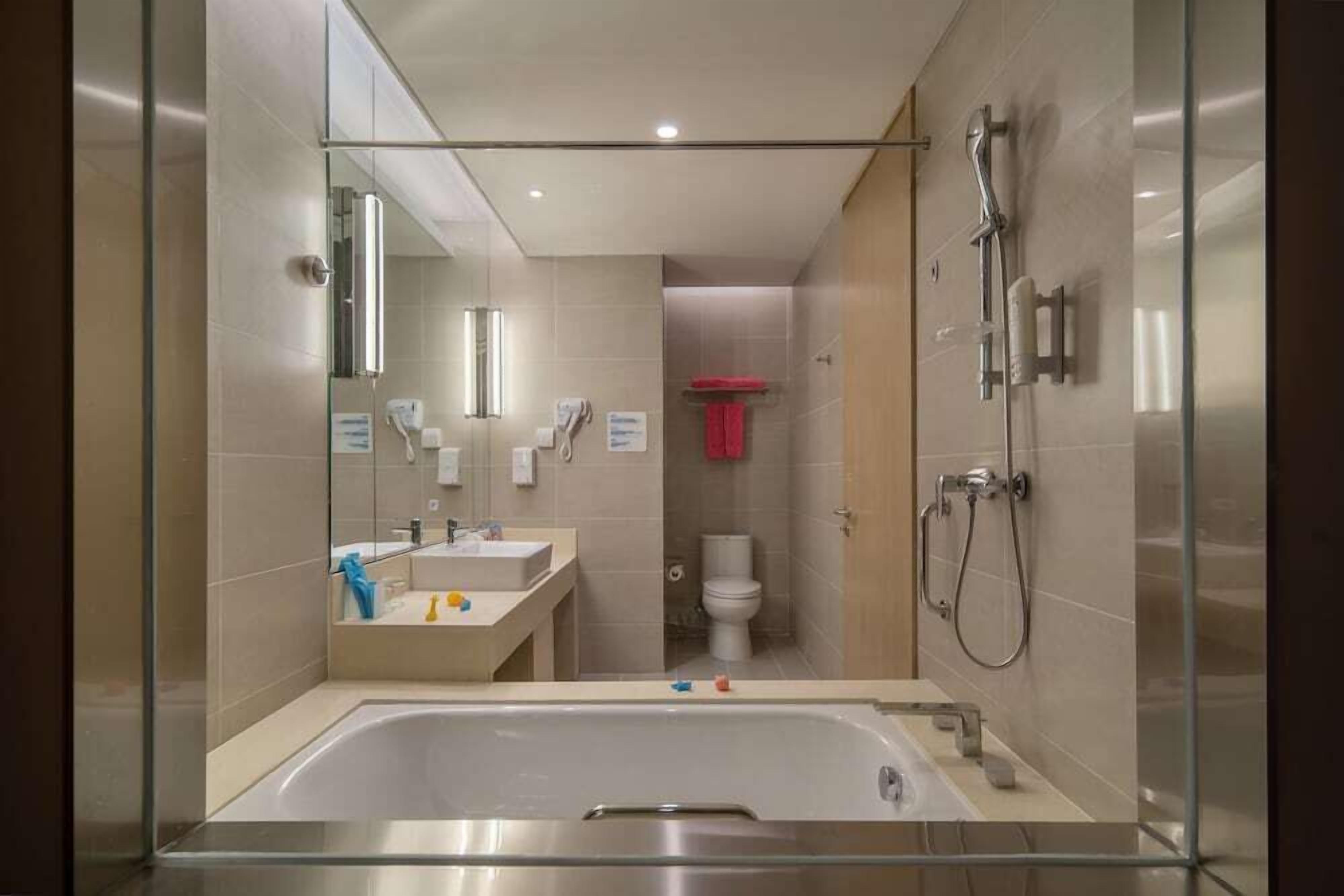 Um banheiro moderno com chuveiro em cabine de vidro, banheira e vaso sanitário.