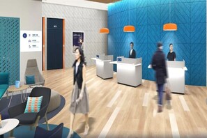 A modern reception area with a blue textured wall, a wooden floor, and a reception desk. There are two receptionists, a woman and a man, and a woman walking by. - Holiday INN Express Qingdao Innovation Park (Qingdao)