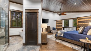 Un dormitorio con cama, ventilador de techo de madera, televisor y ventana con persianas.