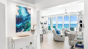 A spacious living area with a ceiling mural, a large window with a view, and a white console table with decorative items. - 2026 Updated, 5-Star, Modern Beachfront Condo at Silver Beach Towers (Destin)